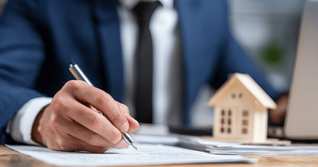 企業主簽署文件畫面，桌面上放置房屋模型，象徵包裝合作、採購合約與長期商業合作關係建立