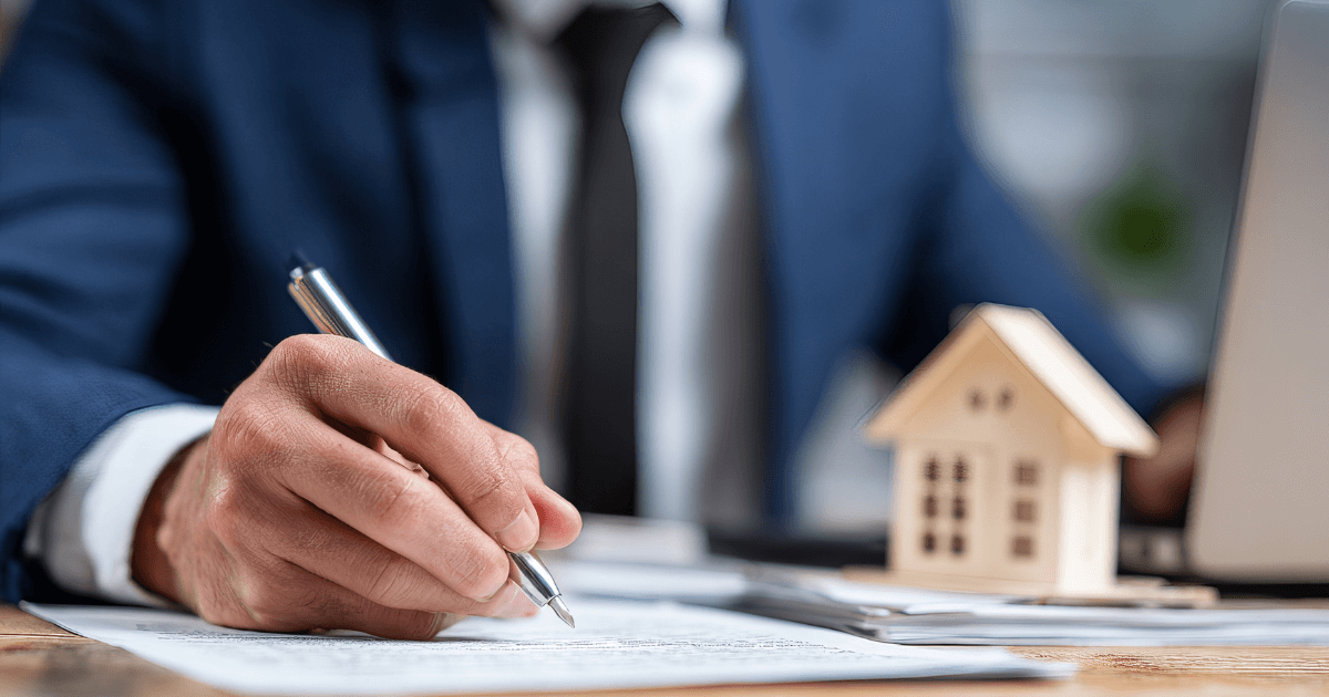 企業主簽署文件畫面，桌面上放置房屋模型，象徵包裝合作、採購合約與長期商業合作關係建立