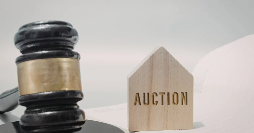 土地拍賣代標費用解析，法槌與房屋模型象徵法拍與標售流程